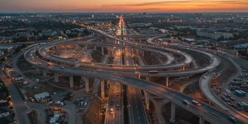 Complex highway interchange under construction at sunset, symbolizing infrastructure investment's financial impact.