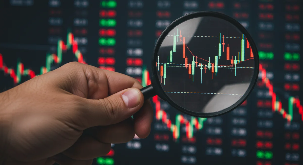 Magnifying glass over stock market ticker, symbolizing investment analysis during monetary policy changes.