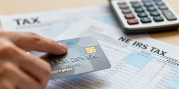 Credit card with tax documents and calculator, symbolizing new IRS tax implications for rewards.